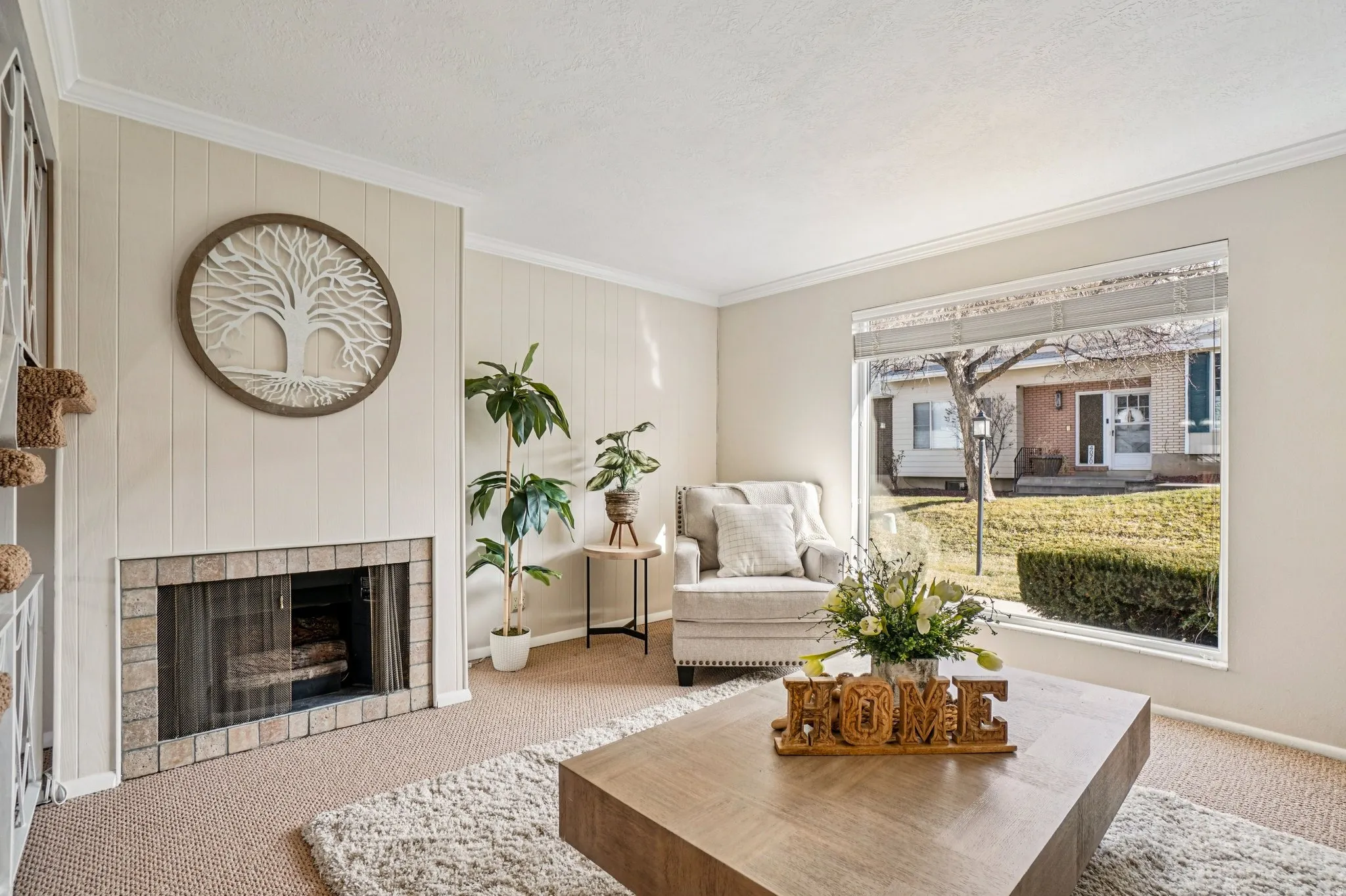 Living area featuring a brick-surround fireplace with a glass screen, a large picture window, textured wall paneling, and wall-to-wall carpet