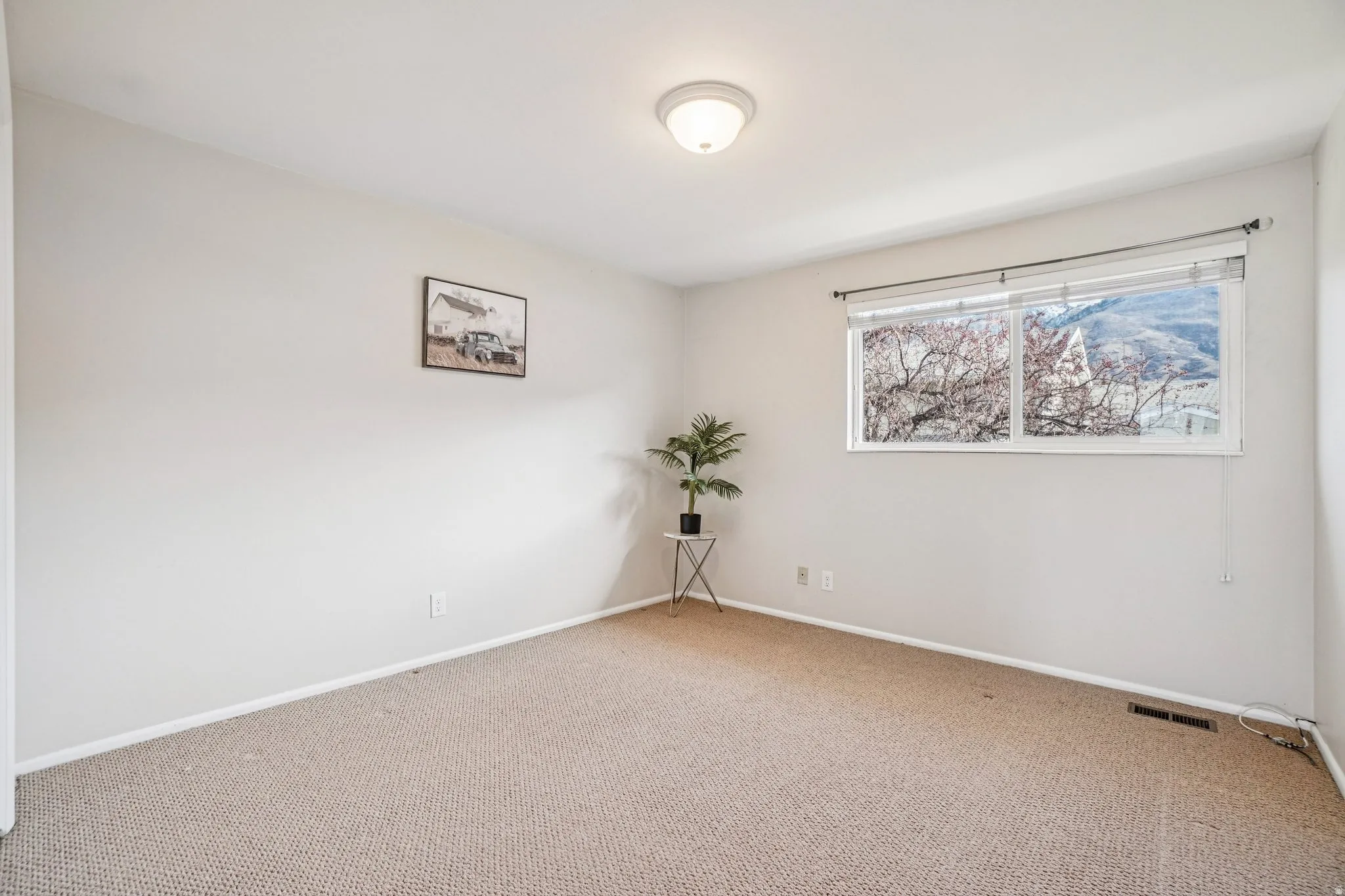 Neutral wall paint and carpeted flooring in a room with a large window