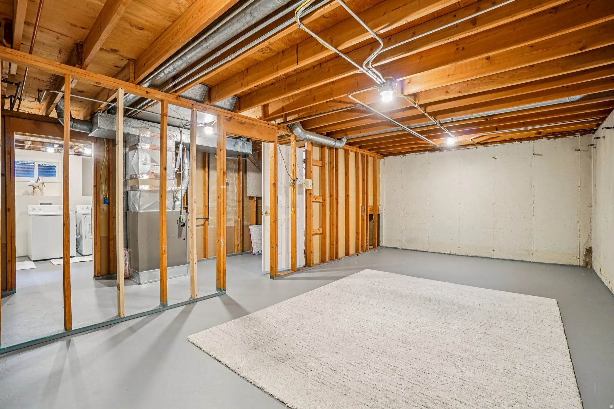 Unfinished basement featuring exposed wood joists and structural framing