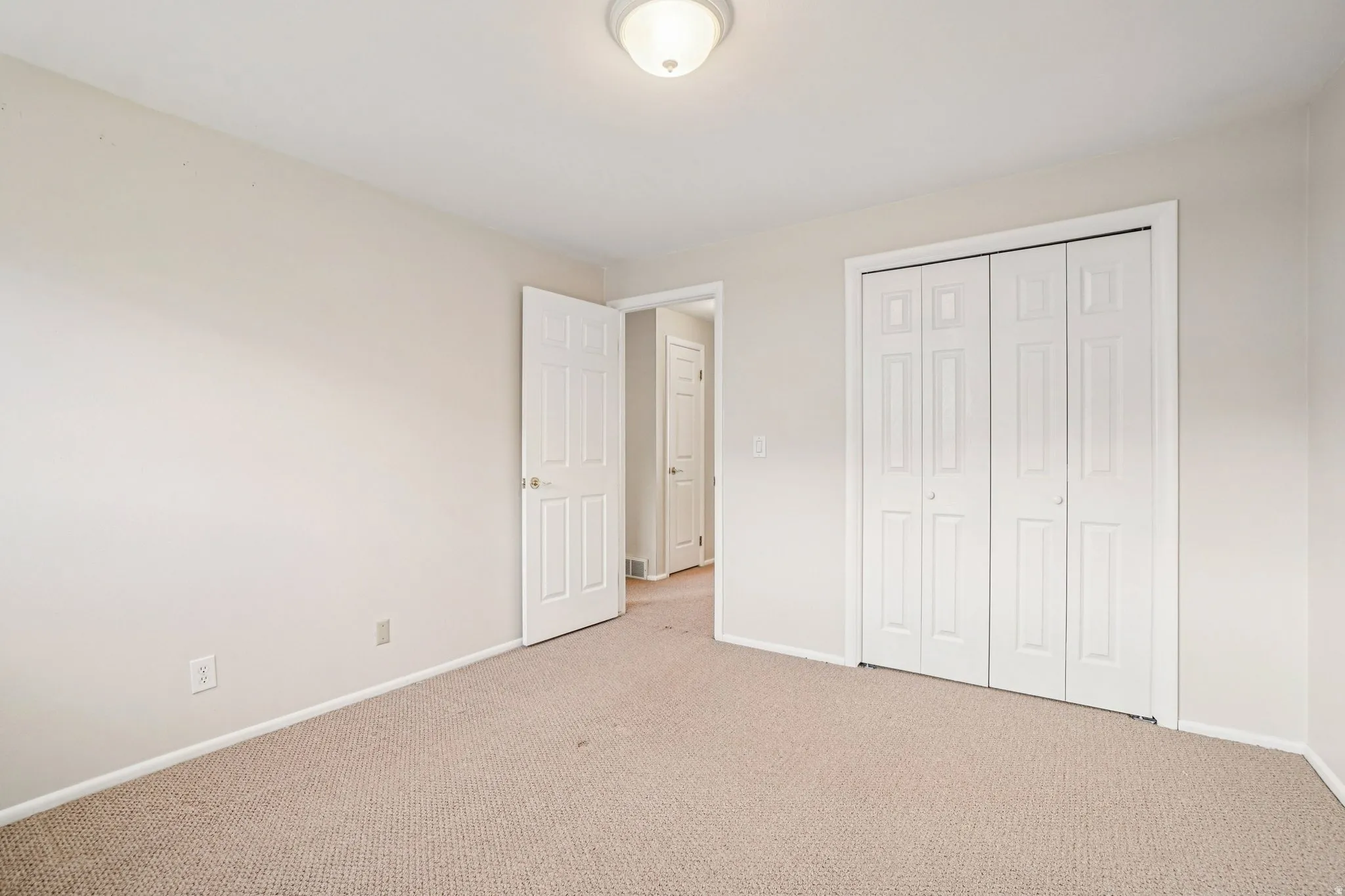 Neutral-toned walls and carpet flooring define this room, featuring a flush-mount ceiling light