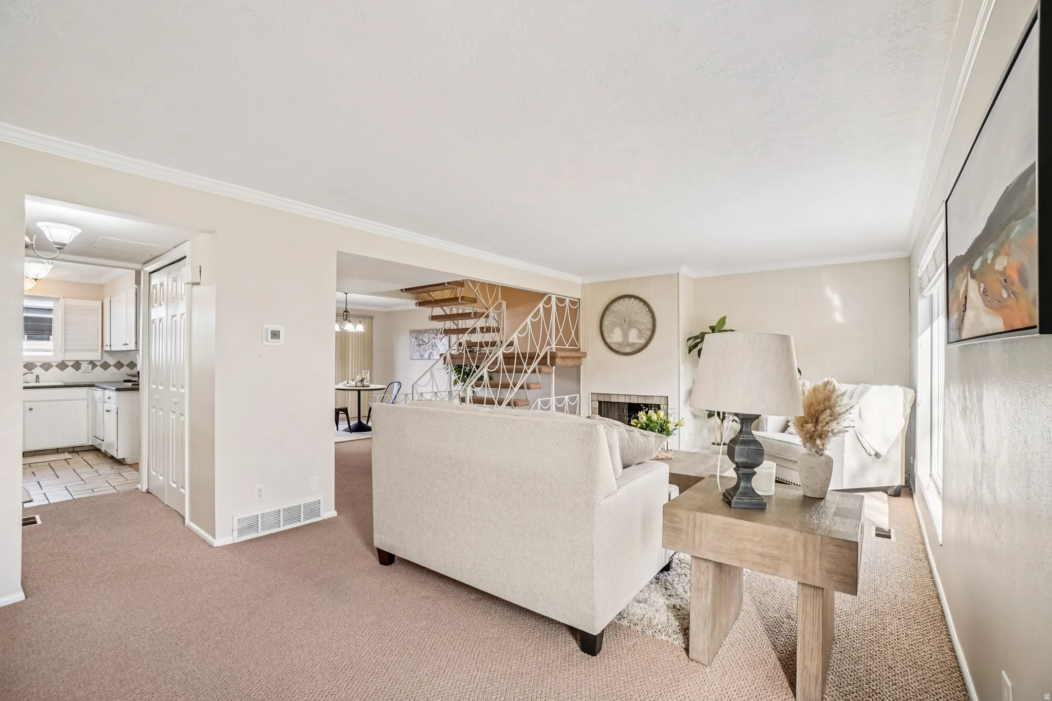 Living area featuring neutral wall tones, crown molding, and carpet flooring