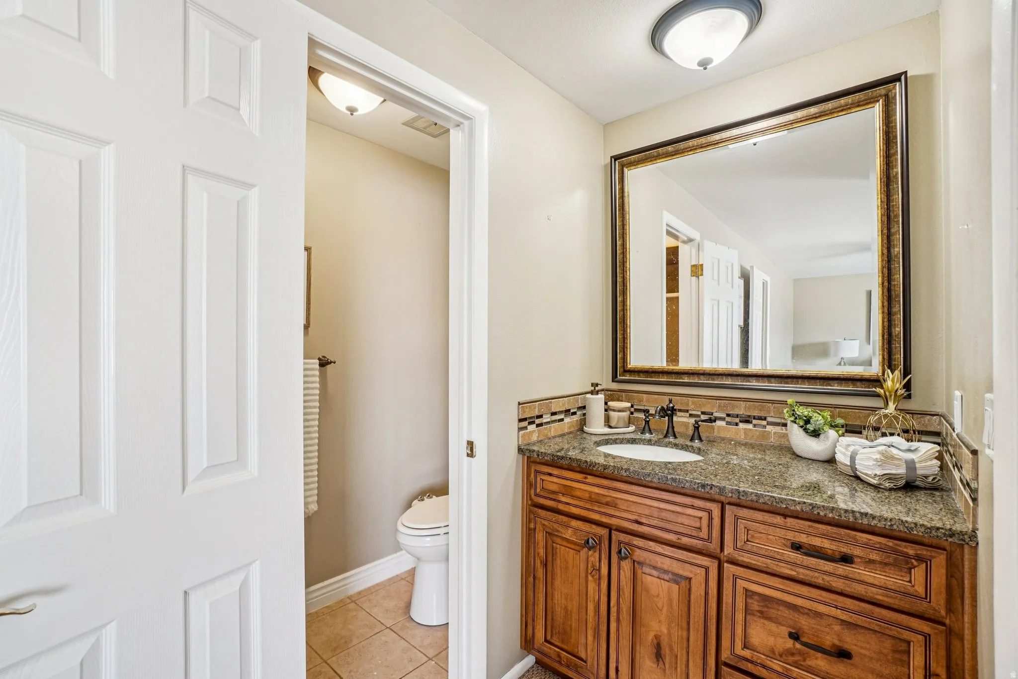Bathroom vanity featuring a granite countertop, undermount sink, and dark wood-finish cabinetry