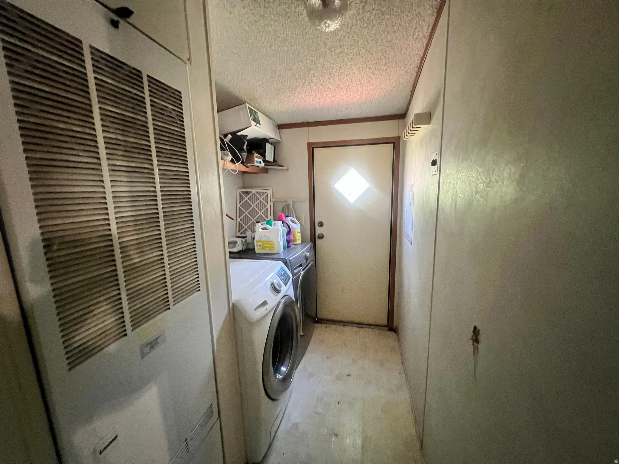 Dedicated utility area featuring a solid door with diamond-shaped lites, vinyl flooring, and a textured ceiling