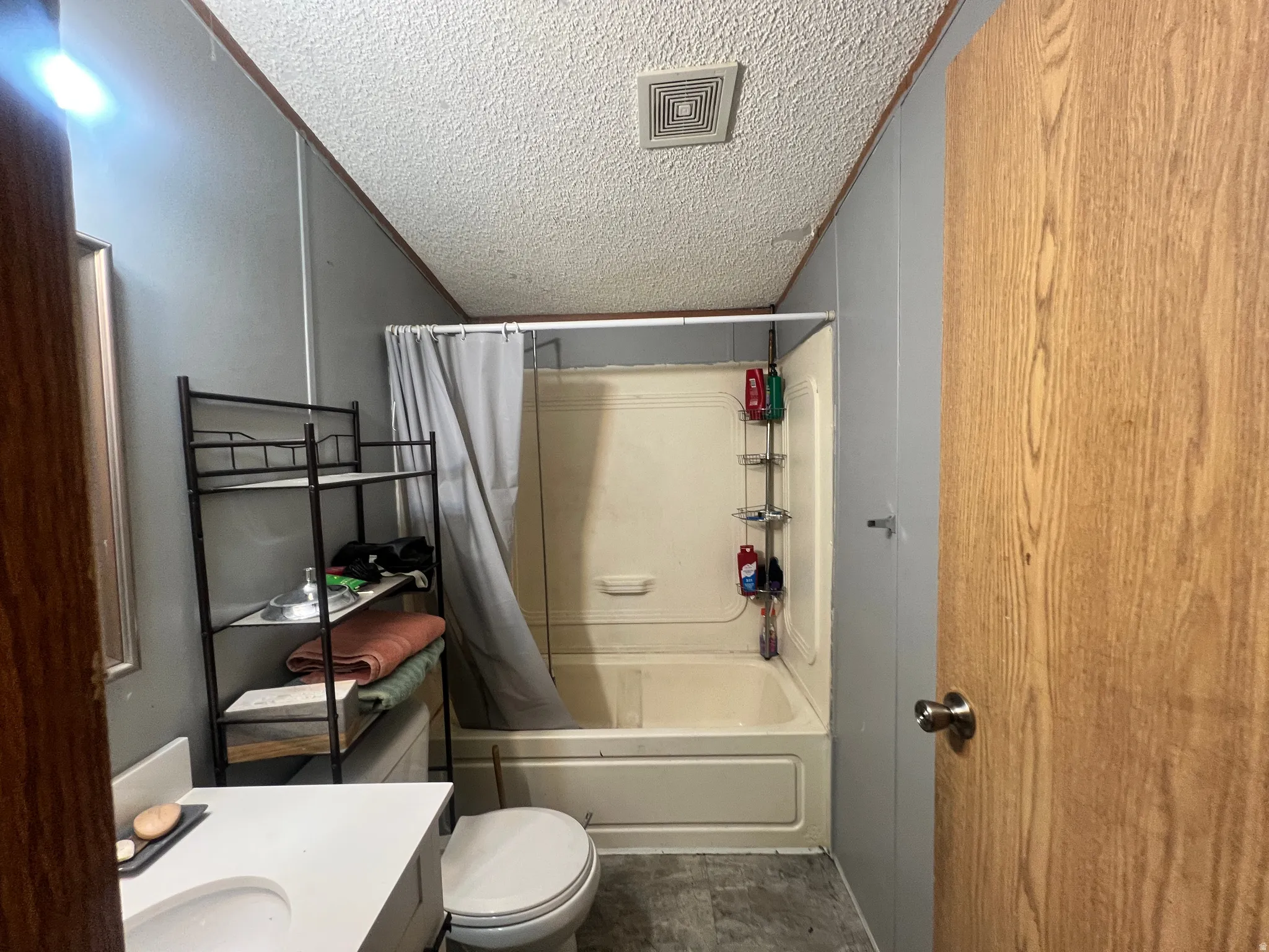 Bathroom featuring a white vanity with an integrated sink, a white toilet, and a combination tub/shower unit
