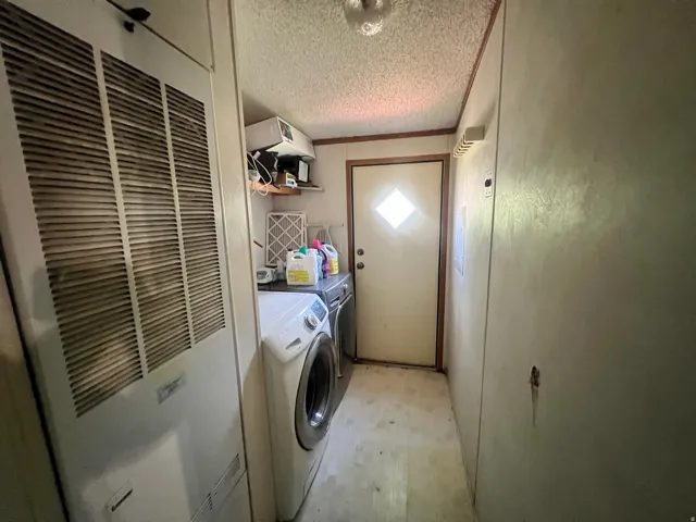 Dedicated utility area featuring a solid door with diamond-shaped lites, vinyl flooring, and a textured ceiling