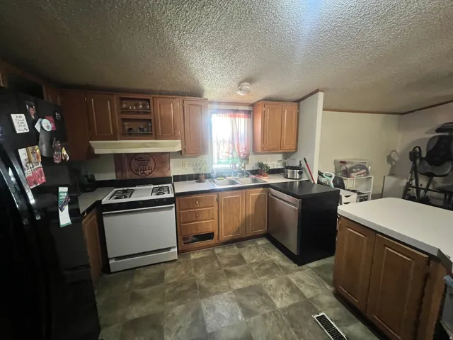 Kitchen featuring wood-finish cabinetry, a white gas range, and a dual-basin stainless steel sink