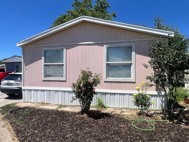 Single-story dwelling with vertical pink siding, white trim, and two front windows