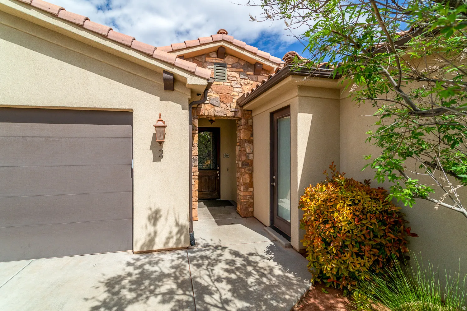 Exterior entry featuring a tile roof, stucco siding, and stone accents