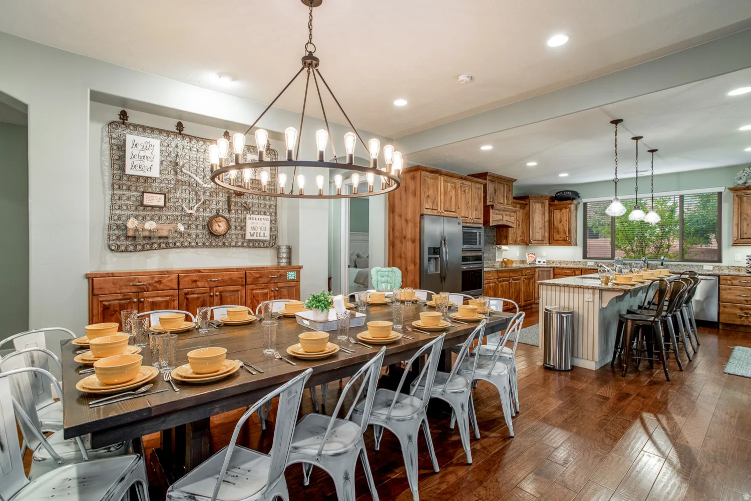 Open-concept kitchen and dining area featuring wood-finish flooring, recessed lighting, and a large window