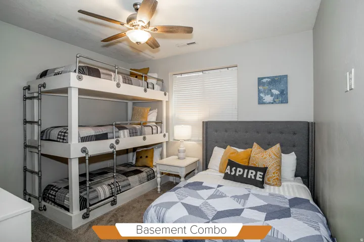 Spacious room featuring triple bunk beds with industrial-style railings, a separate bed with a tufted headboard, and a ceiling fan with integrated lighting