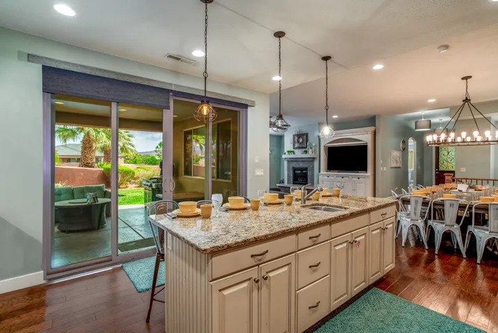 Kitchen island featuring a granite countertop with an undermount sink and pendant lighting
