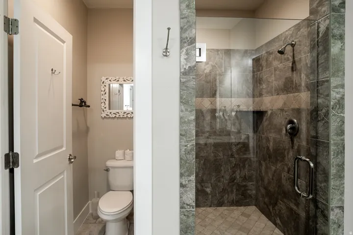 Glass-enclosed shower featuring dark stone-look tile walls, a built-in shower niche, and a contrasting decorative tile band