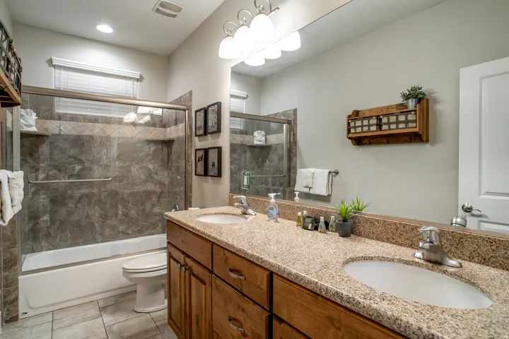 Bathroom featuring a dual vanity with a speckled countertop, undermount sinks, and wood-finish cabinetry