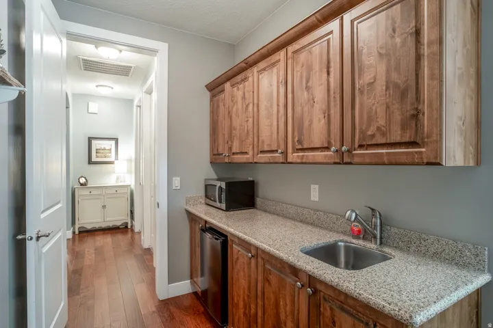 Kitchenette featuring wood cabinetry, speckled countertops, and an undermount sink with a gooseneck faucet