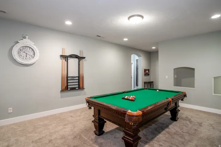 Spacious recreation room featuring recessed lighting, an arched entryway, and a built-in display niche