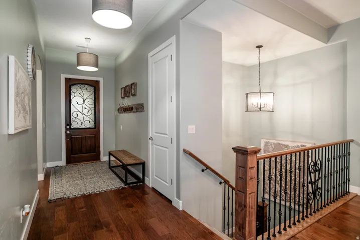 Entryway featuring a dark wood door with decorative ironwork and an overhead drum pendant light