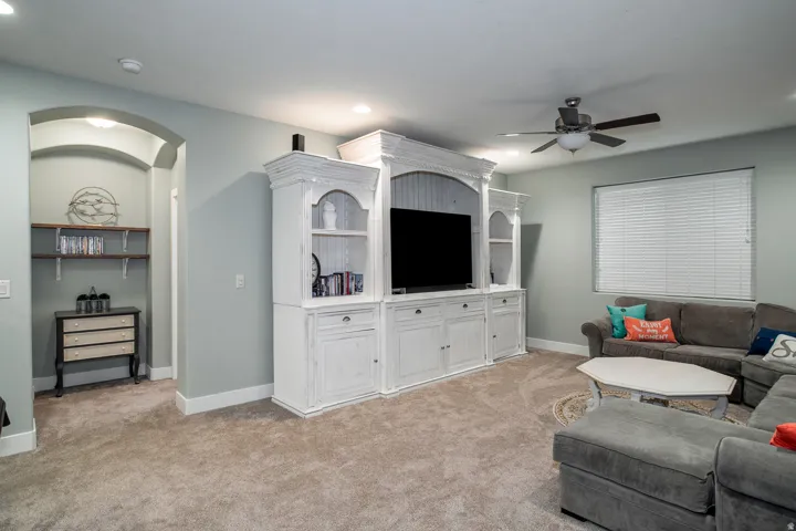 Spacious living area featuring a custom white entertainment center, recessed lighting, and a ceiling fan