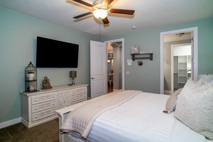 Bedroom featuring light green wall paint, a built-in ceiling fan with lighting, and a wall-mounted flat-screen display
