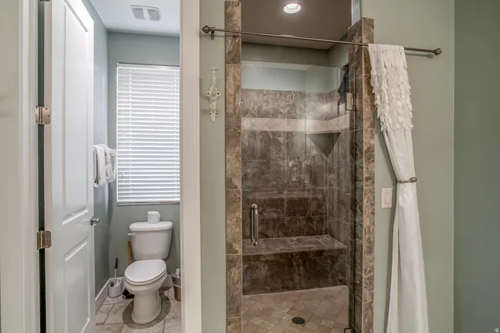 Glass-enclosed shower with a built-in seat and integrated shelving