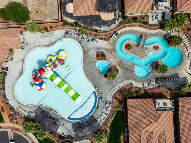 Community aquatic area featuring a large swimming pool with a multi-colored slide structure, a meandering lazy river, and an additional smaller pool