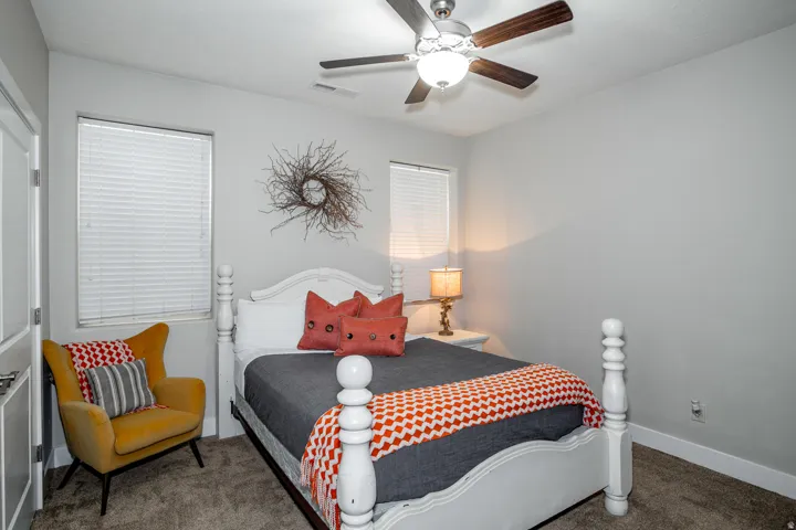 Bedroom featuring light gray walls, white trim, two windows with blinds, a ceiling fan with light fixture, and carpeted flooring