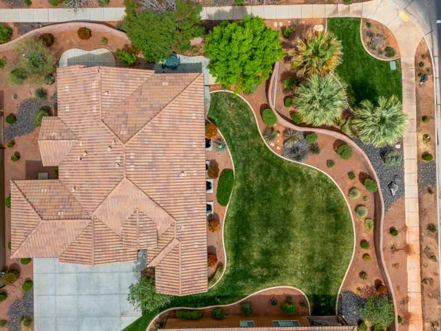 Expansive property featuring a multi-gabled tile roof, concrete driveway, and a large, irregularly shaped green lawn