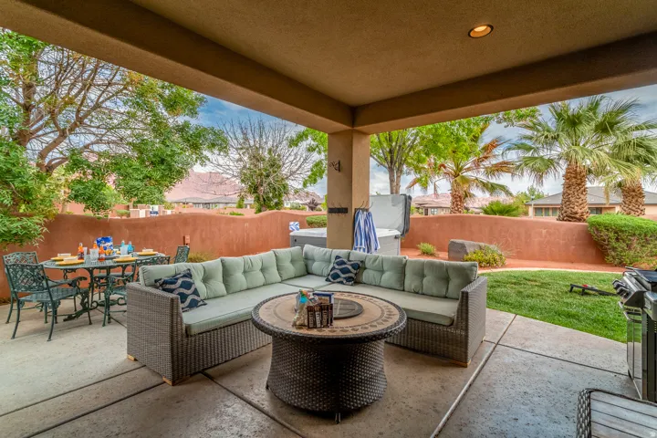 Covered patio featuring concrete flooring, a spa, and a stucco retaining wall