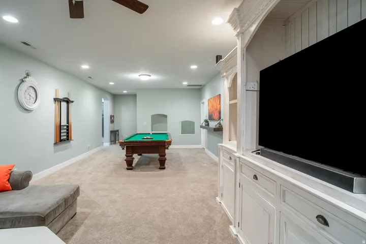 Spacious recreational area featuring recessed lighting, light-toned carpeting, and a built-in media console with cabinet storage