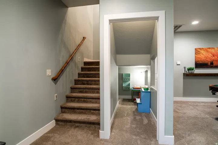 Carpeted staircase with a wood-finish handrail and light gray wall paint
