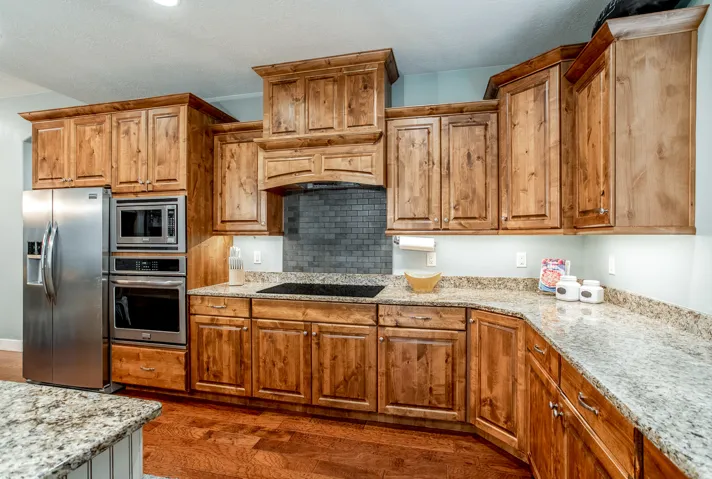 Kitchen featuring light-toned wood cabinetry, granite-finish countertops, stainless steel appliances, and a tile backsplash