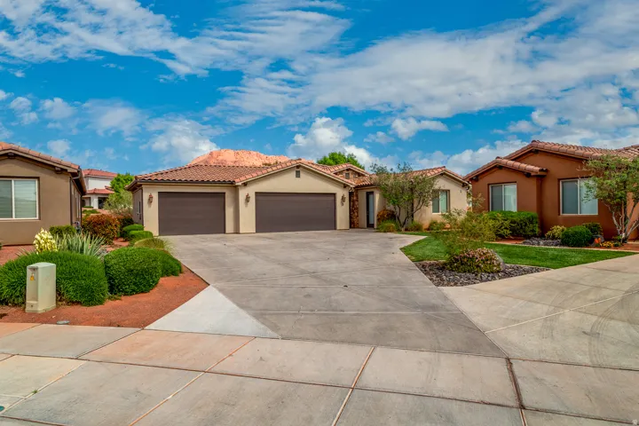 Southwestern-style residence featuring a tile roof, stucco exterior, and an expansive concrete driveway