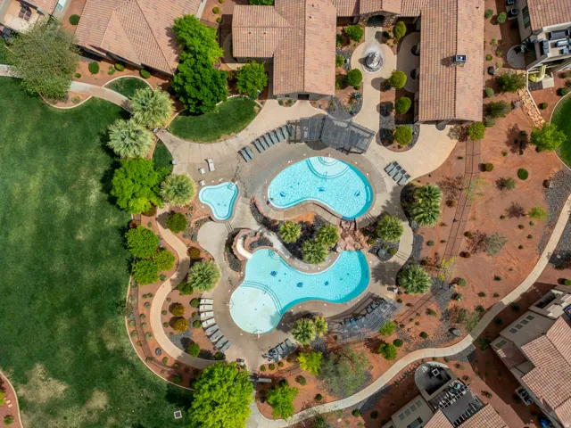 Resort-style pool area featuring two freeform pools, surrounding lounge seating, and lush landscaping