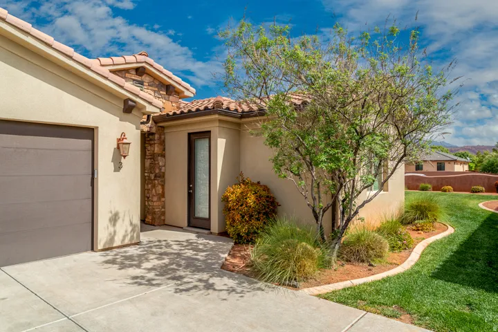 Stucco exterior featuring a tile roof, stone façade accents, a dark wood-finish garage door, and a front entry door with a vertical glass insert