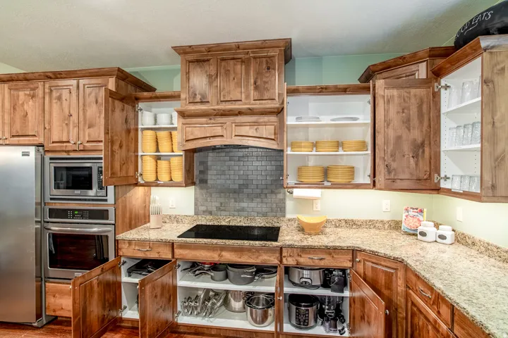 Kitchen featuring wood cabinetry, light-toned countertops, stainless steel appliances, and a tiled backsplash