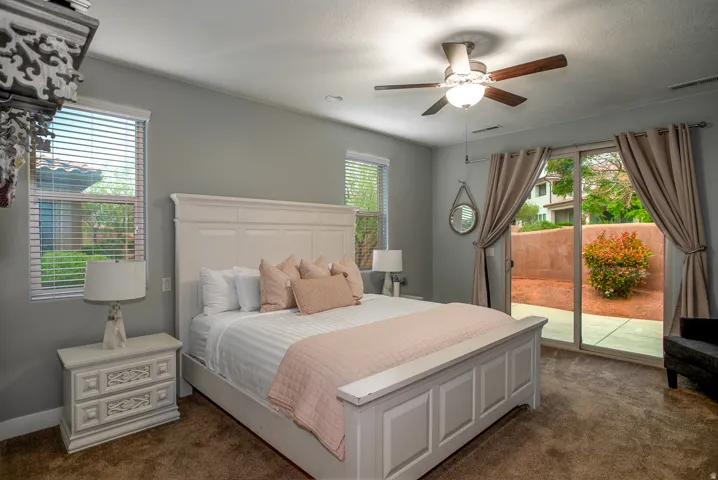 Interior room featuring light gray walls, brown carpet flooring, and a ceiling fan with light fixture