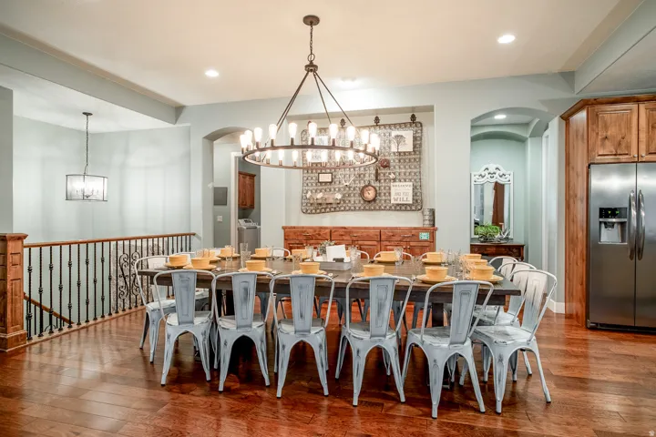 Spacious dining area featuring wood-finish flooring, a large iron chandelier, built-in wooden cabinetry, and stainless steel appliances