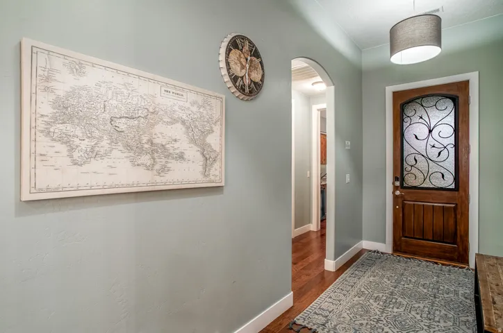 Arched entryway leading to an interior space with wood-finish flooring