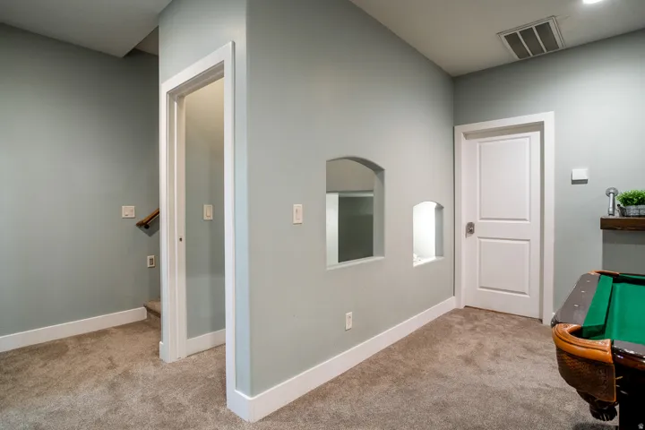 Interior hallway featuring light gray wall paint, white trim, and carpeted flooring