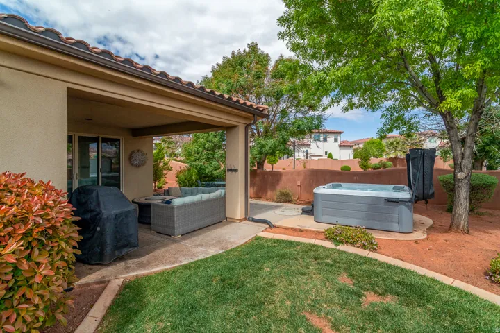 Private backyard featuring a covered patio, a built-in hot tub, and a manicured lawn area