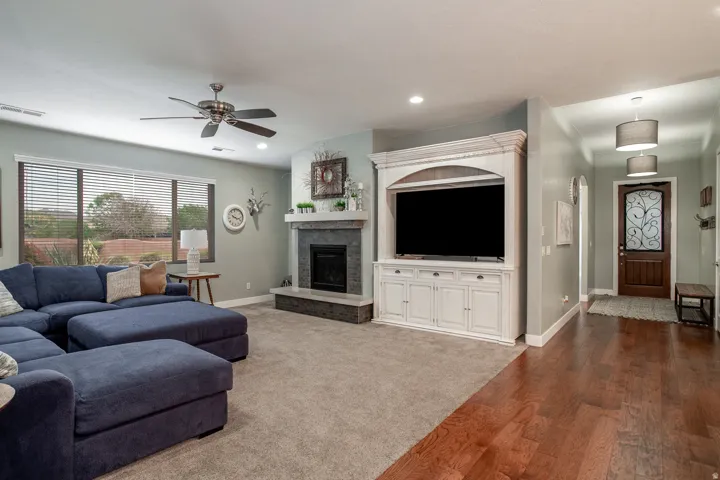 Expansive living area featuring a built-in entertainment center, a fireplace with a stone surround and hearth, and large windows with horizontal blinds