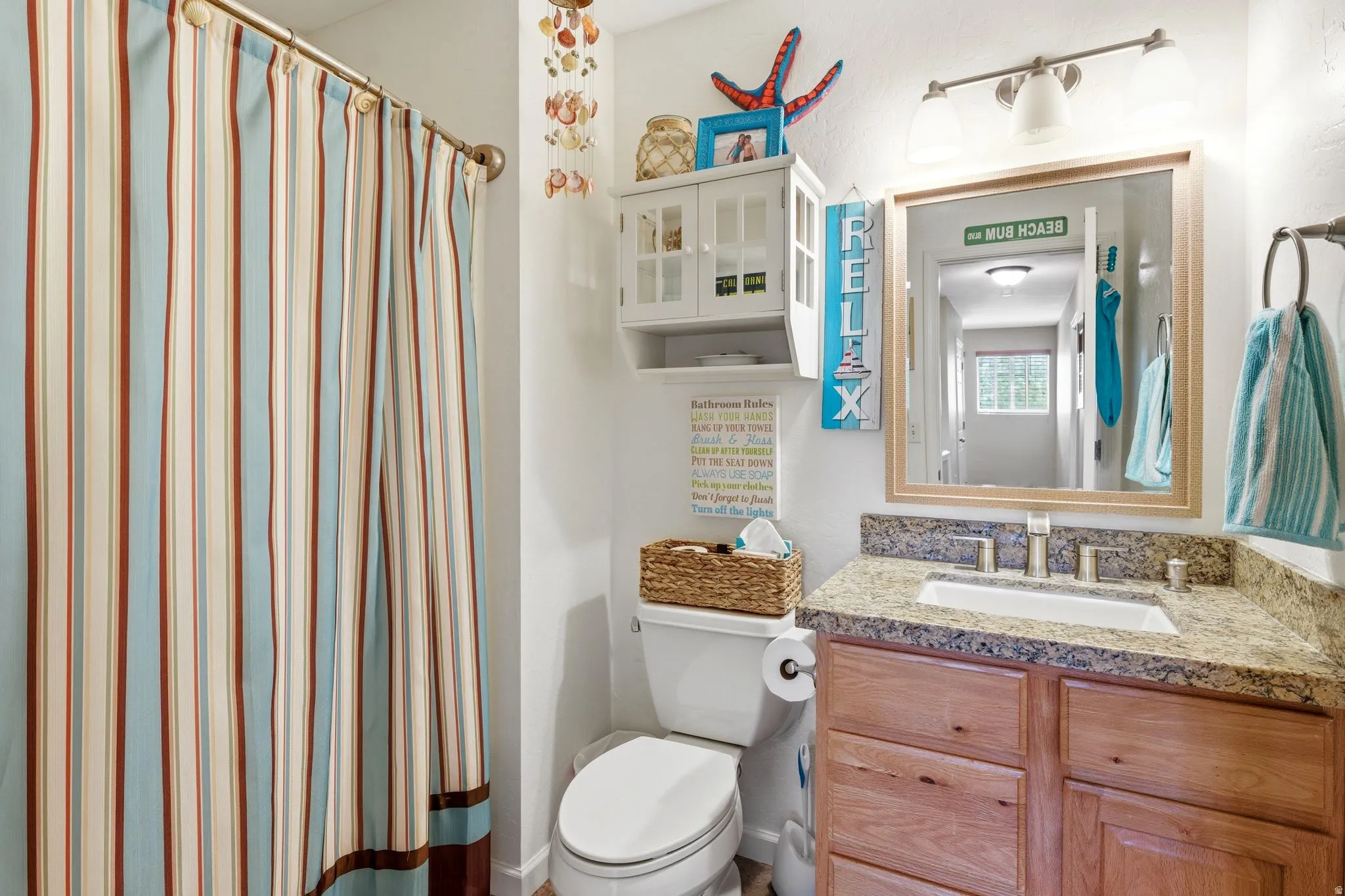 Bathroom featuring a vanity with a granite-style countertop, undermount sink, and wood-finish cabinetry