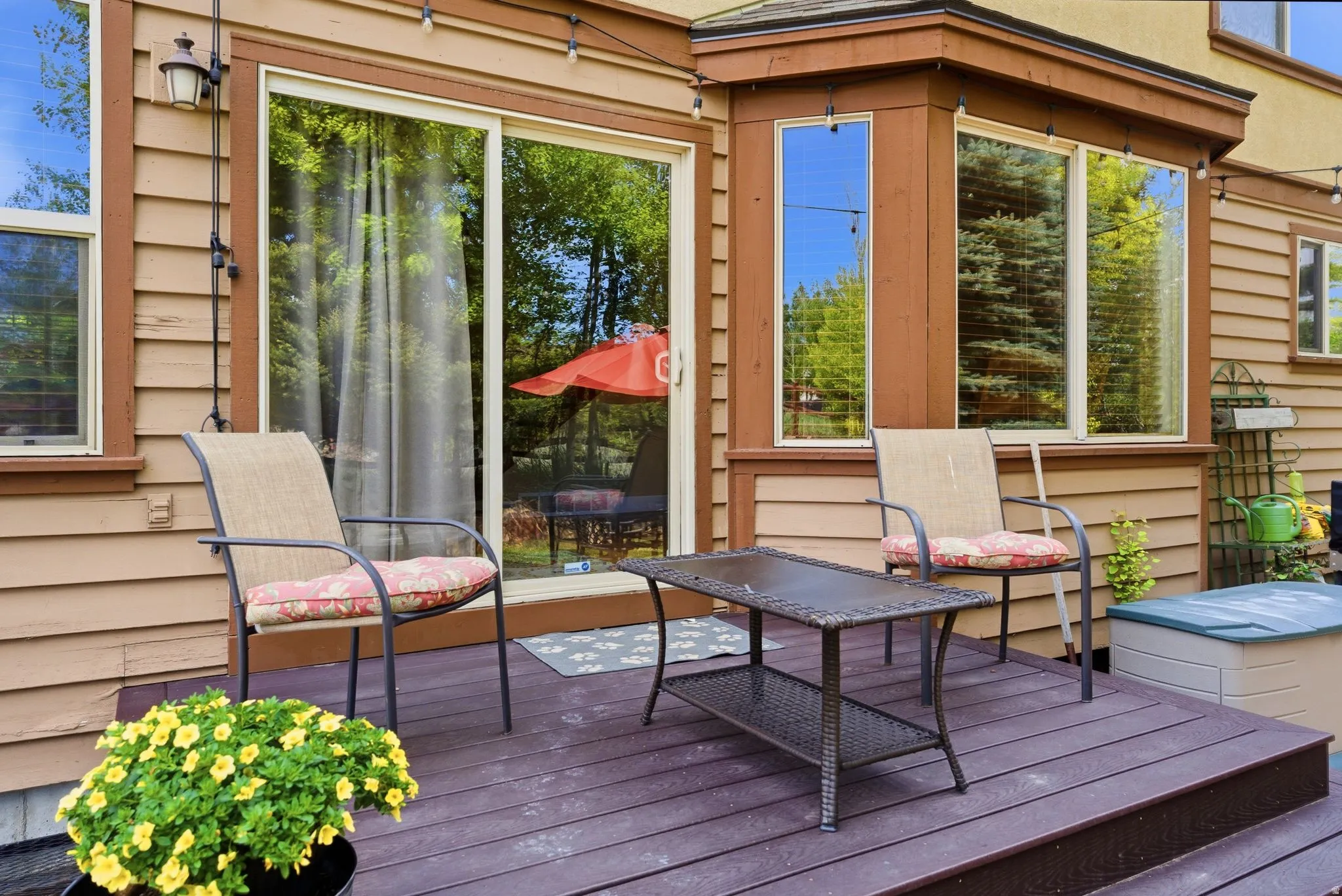 Wood-finish deck with a sliding glass door and multiple windows providing ample natural light