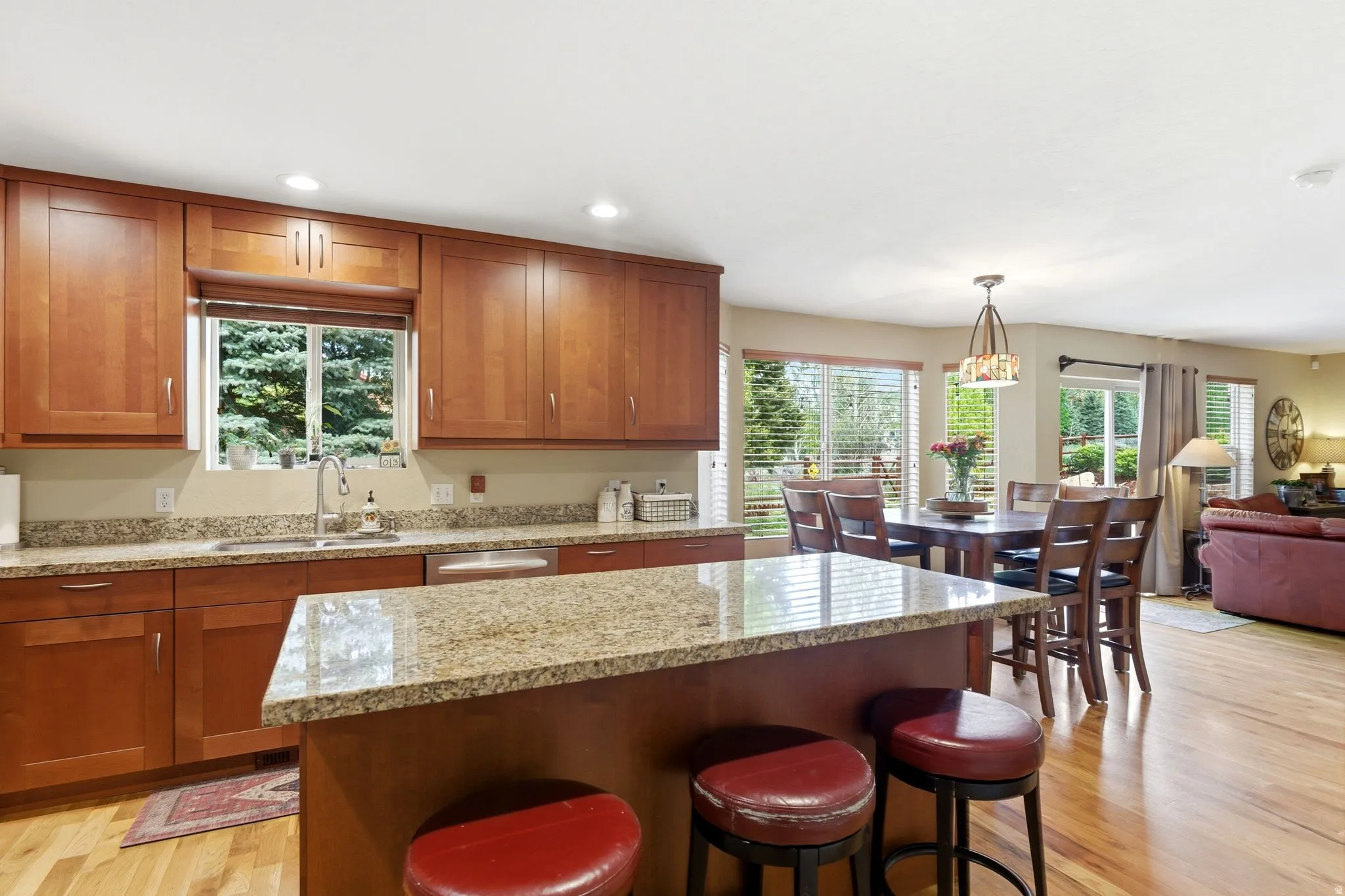 Kitchen featuring natural wood cabinetry, light-toned granite countertops, a stainless steel sink with a gooseneck faucet, and recessed lighting