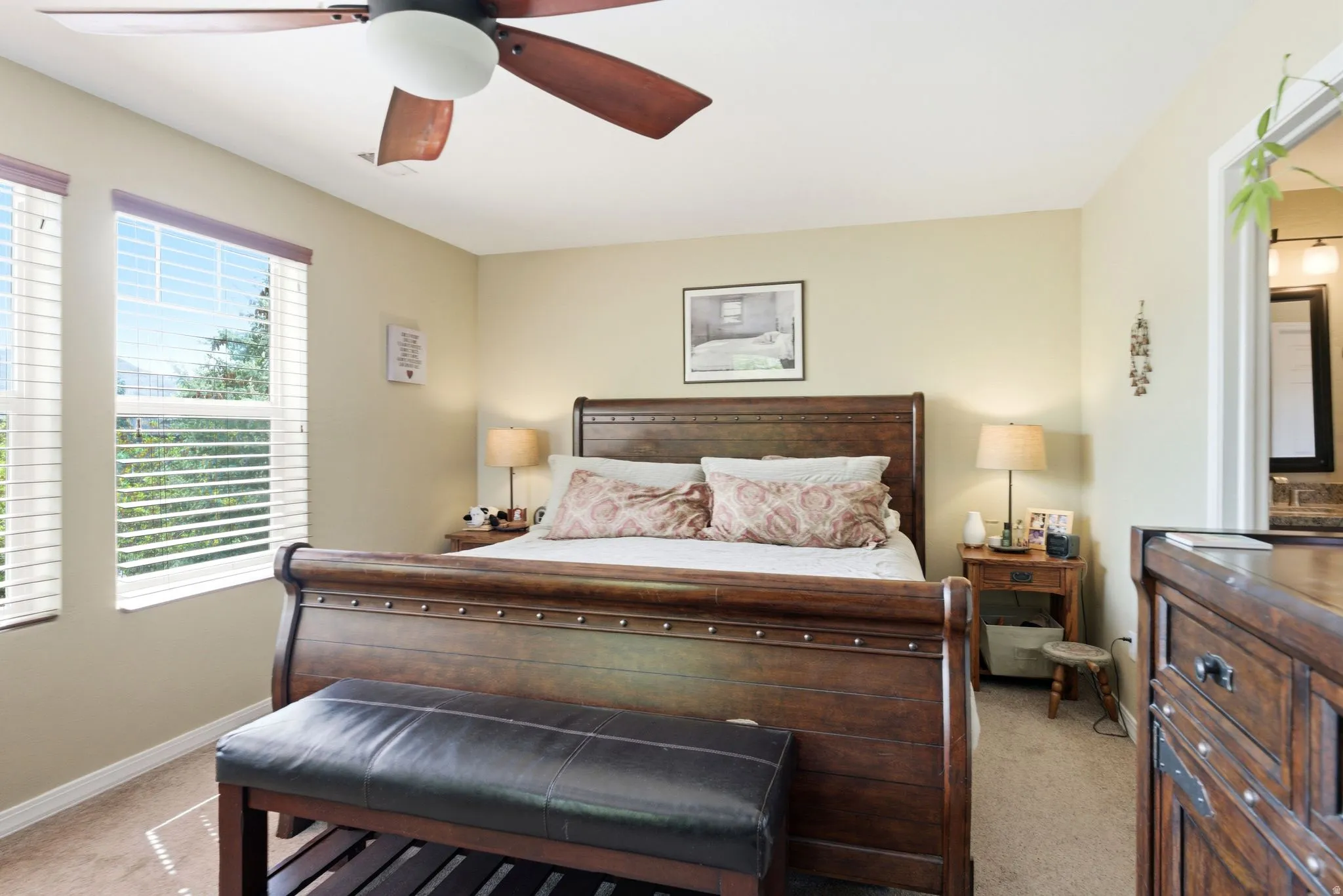 Bedroom featuring a ceiling fan with integrated lighting, two windows with blinds, and neutral tone wall paint