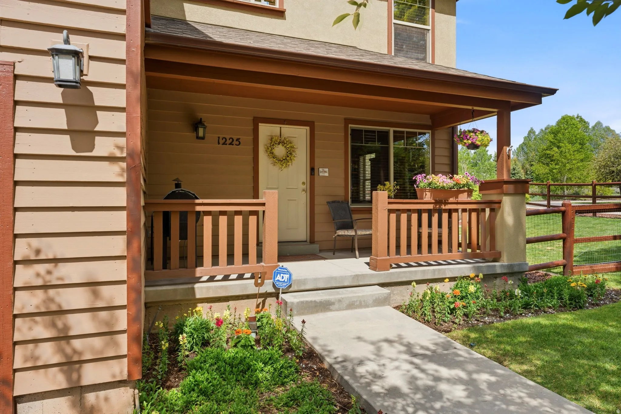 Covered front porch featuring wood-toned railing, a light-colored entry door, and concrete steps