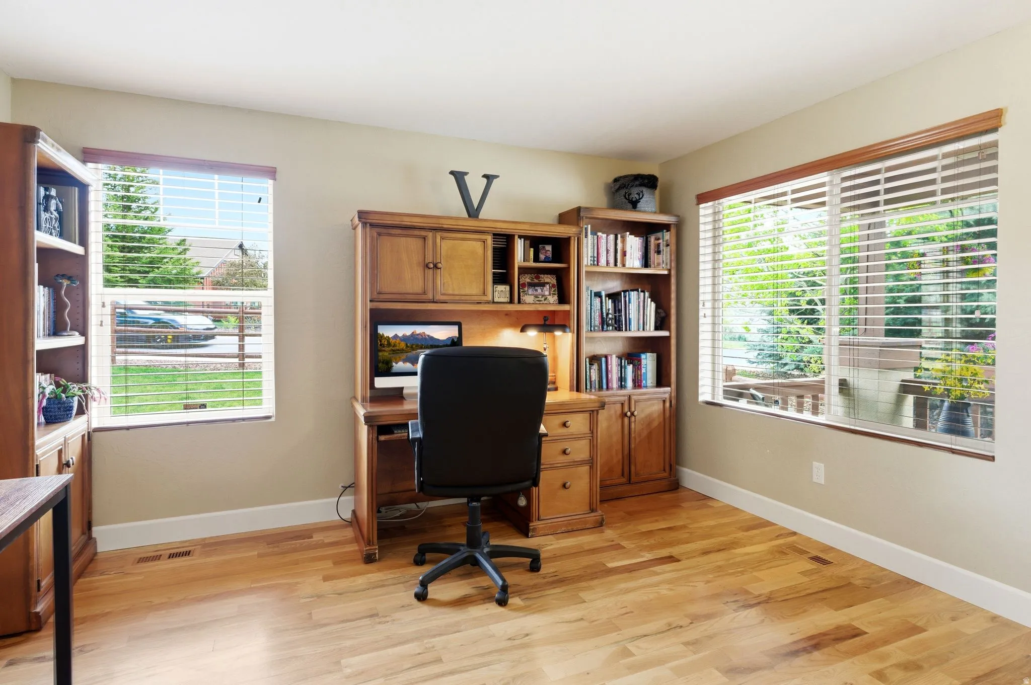 Room featuring two large windows, light-toned walls, and wood-finish flooring