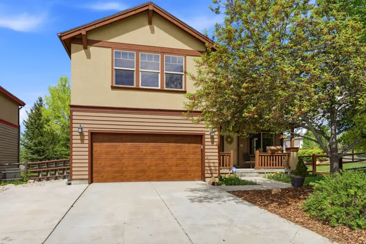 Exterior featuring a wood-finish garage door, stucco siding, and a covered front porch with wood railings
