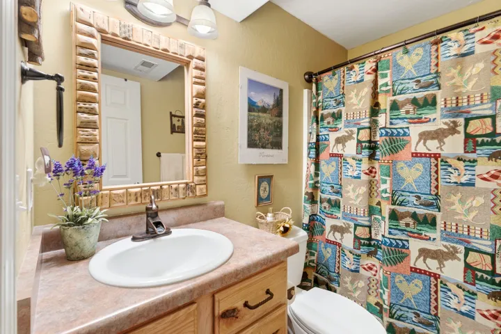 Bathroom featuring a wood-framed mirror, a sink with a bronze-finish faucet, and a light-toned countertop