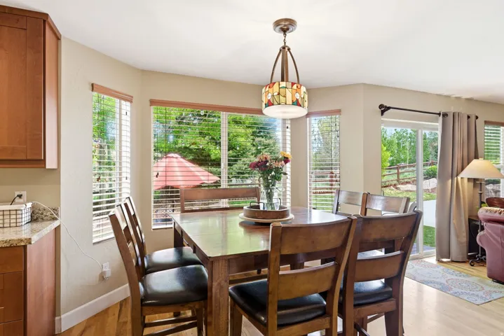 Dining area featuring a decorative chandelier, bay windows with blinds, and wood-finish flooring