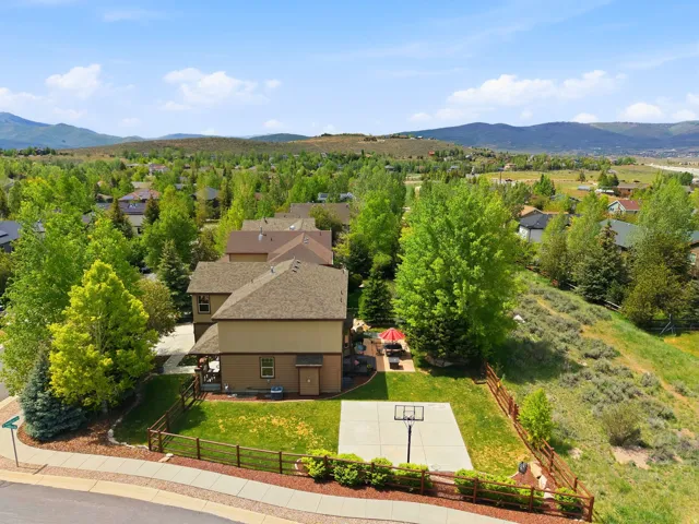Expansive backyard featuring a concrete sport court, green lawn, and wood fencing
